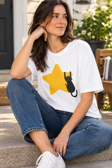 Cat Reaching for Star T-Shirt worn by a young woman sitting on a porch