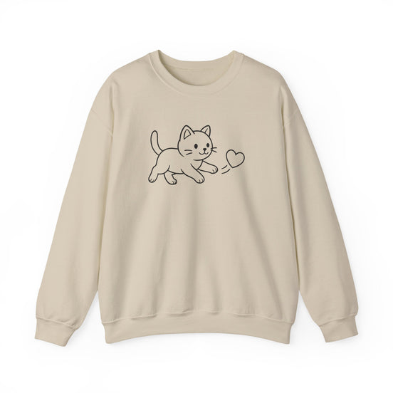 A beige crewneck sweatshirt featuring a simple black line art graphic of a kitten playing with a heart on the chest, displayed against a clean white background.