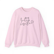 A light pink crewneck sweatshirt featuring a simple black line art graphic of a cat chasing a  small heart on the chest, displayed against a clean white background.