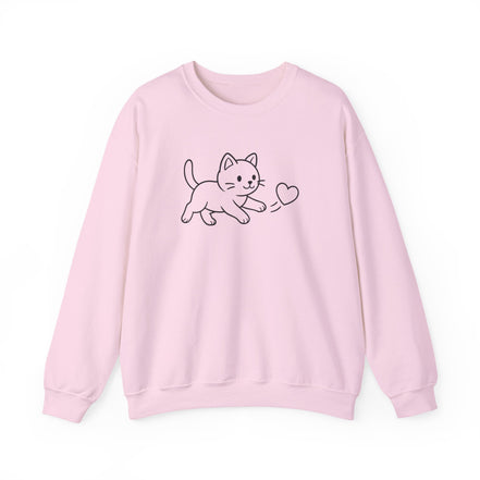 A light pink crewneck sweatshirt featuring a simple black line art graphic of a cat chasing a  small heart on the chest, displayed against a clean white background.