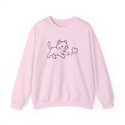 A light pink crewneck sweatshirt featuring a simple black line art graphic of a cat chasing a  small heart on the chest, displayed against a clean white background.
