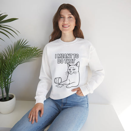Woman wearing a white sweatshirt with a blue graphic and text, sitting on a white surface with a plant in the background.